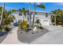 Two-story coastal home featuring lush landscaping and a two-car garage at 9 Palm Harbor Dr, Holmes Beach, FL 34217