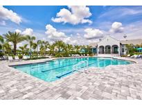 A luxurious community pool surrounded by lounge chairs and palm trees offers a relaxing atmosphere at 2720 Butterfly Jasmine Trl, Sarasota, FL 34240