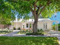 Charming home with a covered porch, white facade, and mature tree providing shade at 3629 Almeria Ave, Sarasota, FL 34239