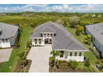 Stunning aerial view of a modern home with lush landscaping and a paver driveway in a serene setting at 8364 Sea Glass Ct, Sarasota, FL 34240