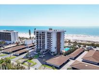 Beautiful aerial view of a beachfront condo with a pool, lush landscaping, and beach access at 101 Benjamin Franklin Dr # 63, Sarasota, FL 34236