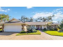 Charming single-story home with stone accents, a tile roof, mature landscaping, and a purple front door at 3876 Torrey Pines Blvd, Sarasota, FL 34238