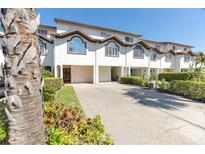 Charming townhome features a well-manicured lawn, two-car garage, and distinctive architectural details at 285 Madeira Cir, Tierra Verde, FL 33715