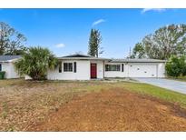 Charming single story home with a well-manicured lawn, beautiful landscaping and a vibrant red front door at 3016 Taunton W Dr, Bradenton, FL 34205