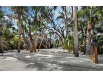 Charming raised beach house with a driveway shaded by mature palms and live oaks at 3376 S Seclusion Dr, Sarasota, FL 34239