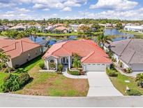 Aerial view of a single-Gathering home with red tile roof near a lake and lush landscaping at 4173 Hearthstone Dr, Sarasota, FL 34238