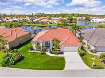 Beautiful waterfront home with lush landscaping, a tile roof, and a lovely circular window on a sunny day at 4173 Hearthstone Dr, Sarasota, FL 34238