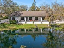 Charming home with a covered porch overlooking a serene pond, complemented by mature trees and landscaping at 4540 Murdock Ave, Sarasota, FL 34231