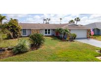 Charming single-story home features a well-manicured lawn and tropical landscaping at 5859 Lincoln Rd, Venice, FL 34293