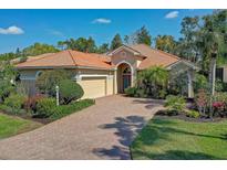 Beautifully landscaped single-story home featuring a red tile roof and brick paved driveway at 7762 Us Open Loop, Lakewood Ranch, FL 34202