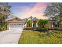 Charming single-story home with a well-manicured lawn, lush greenery, and a two-car garage under a picturesque sky at 8122 Spring Marsh Dr, University Park, FL 34201