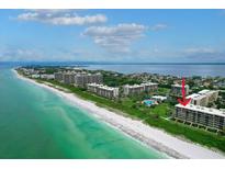 Stunning aerial view of the beach and condo community with crystal clear turquoise water at 1055 Gulf Of Mexico Dr # 405, Longboat Key, FL 34228