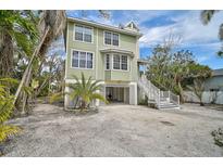 Charming two-story home with a light green exterior, white trim and beautiful tropical landscaping at 123 Faubel St, Sarasota, FL 34242