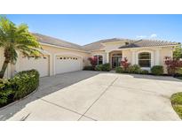 Elegant home featuring a barrel tile roof, a spacious driveway, and a lush tropical landscaping in the front yard at 12736 Penguin Dr, Bradenton, FL 34212