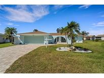 Charming single-story home with a well-manicured lawn, palm trees, and a paved driveway leading to a two-car garage at 1714 Coral Sands Ct, Venice, FL 34293