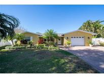 Charming single-story home with a manicured lawn, mature landscaping, and a brick paver driveway at 1940 35Th N St, St Petersburg, FL 33713