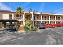 Beige condo building with carport and well-maintained landscaping, and multiple cars parked in the lot at 2526 Clubhouse Dr # 203, Sarasota, FL 34232