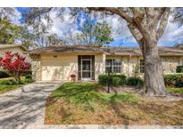 Charming single-story home features a lush lawn, a covered porch, and a one-car garage at 4223 Oakhurst E Cir # 3025, Sarasota, FL 34233