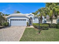 Charming single-story home with a manicured lawn, brick driveway, and tropical landscaping at 5261 Highbury Cir, Sarasota, FL 34238