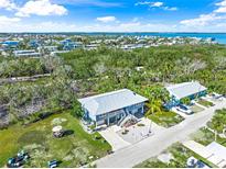 Captivating aerial view of a coastal home featuring lush greenery and views of the beautiful blue water at 691 Gulf Bay Rd, Longboat Key, FL 34228