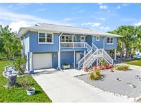 Charming two-story home featuring a garage, front porch, and stairs, all surrounded by lush landscaping at 691 Gulf Bay Rd, Longboat Key, FL 34228