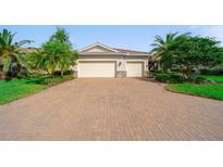 Exterior view of home showing three-car garage, beautiful landscaping, and brick-paved driveway at 8007 River Preserve Dr, Bradenton, FL 34212