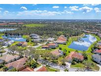 Aerial view of a beautiful neighborhood with tile-roofed homes, lush greenery, and sparkling lakes under a blue sky at 9612 Old Hyde Park Pl, Bradenton, FL 34202