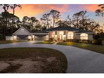 Beautifully landscaped home with a circular driveway and spacious three-car garage and a colorful sunset at 13608 11Th E Ter, Bradenton, FL 34212