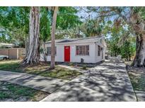 Charming single-story home with white siding, a bright red door, and mature landscaping at 1664 10Th St, Sarasota, FL 34236