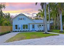 Charming two-story home with a gravel driveway, light blue shutters, and lush tropical landscaping at 206 23Rd W St, Bradenton, FL 34205