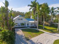 Charming two-story home featuring a metal roof, light blue shutters, gravel driveway and lush landscaping at 206 23Rd W St, Bradenton, FL 34205