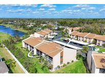 An aerial view of a condominium complex near a lake and green spaces provides a serene and appealing living environment at 2446 Clubhouse Cir # 202, Sarasota, FL 34232