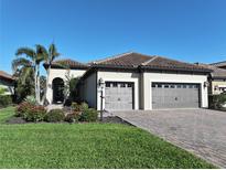 Charming home with a tile roof, three-car garage, palm trees, and meticulous landscaping at 26800 Pavin Dr, Englewood, FL 34223