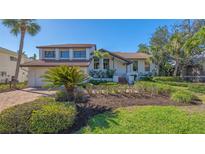 Inviting two-story home featuring manicured landscaping, a red tile roof and a brick paver driveway at 3151 Bayou Sound, Longboat Key, FL 34228