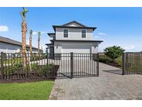 Charming two-story home with a manicured lawn, iron gate and paved driveway at 44240 Creekside Run Ln, Punta Gorda, FL 33982