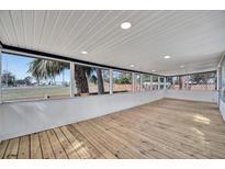 Bright sunroom with wood floors and large windows offering scenic views of the surrounding landscape at 5061 Placida Rd # A, Englewood, FL 34224
