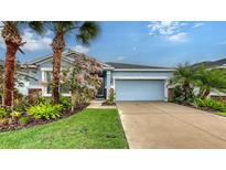 Charming single-story home with a well-manicured lawn, featuring a two-car garage and colorful landscaping at 5068 Inshore Landing Dr, Apollo Beach, FL 33572