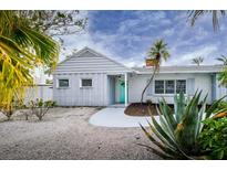 Charming single-story home with a cheerful teal door and tropical landscaping at 552 Juan Anasco Drive, Longboat Key, FL 34228