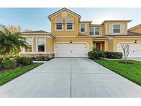 Inviting two-story home featuring a yellow facade, attached two-car garage, and a well-maintained lawn with decorative landscaping at 11474 Rolling Green Dr, Bradenton, FL 34211