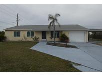 Charming one-story home with a well-maintained lawn, a palm tree and an attached garage at 1717 Alton Rd, Port Charlotte, FL 33952