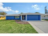 Charming one-story home featuring a well-manicured lawn and a blue exterior paint scheme with matching garage door at 2434 Carlisle Pl, Sarasota, FL 34231