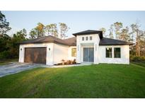 Beautiful single Gathering home with a lush green lawn, brown garage door, and a light blue double-door entry at 2760 Adele St, North Port, FL 34291