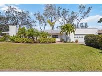 Charming home featuring a well-manicured lawn and lush landscaping with mature trees and vibrant greenery at 317 Harbor S Dr, Venice, FL 34285