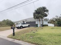 Charming single-story home featuring a well-maintained lawn, two palm trees, and a driveway with a parked car at 3650 S Sumter Blvd, North Port, FL 34287