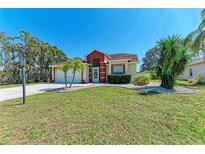 Lovely home with lush green lawn, landscaped with palm trees and brick-lined garden beds at 5103 73Rd E St, Bradenton, FL 34203