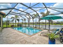 Enclosed pool with lake view, an umbrella, and tiled deck, surrounded by palm trees at 5656 Cantucci St, Nokomis, FL 34275
