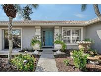 Charming home featuring a vibrant blue front door flanked by decorative planters and a stone fountain at 6684 Easton Dr, Sarasota, FL 34238