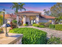 Beautiful home exterior with lush landscaping, stone pathway, and a terracotta tile roof at 6900 Country Lakes Cir, Sarasota, FL 34243