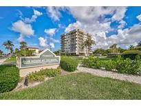 Beautiful condominium building, Our House at the Beach, featuring lush landscaping and blue skies in a tropical location at 1001 Beach Rd # A203, Sarasota, FL 34242