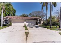 Charming home featuring a tile roof, attached two-car garage, and lush landscaping at 3815 Muirfield Ct, Palm Harbor, FL 34685